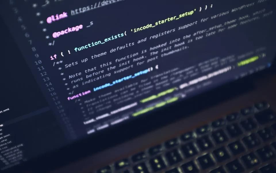 Close-up of code on a laptop screen in a dark room.